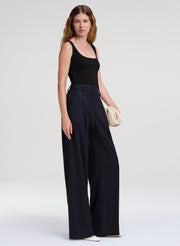 Woman wearing a black sleeveless top and wide-leg pants on a white background