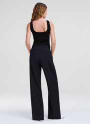 Woman wearing a black sleeveless top and wide-leg pants on a white background