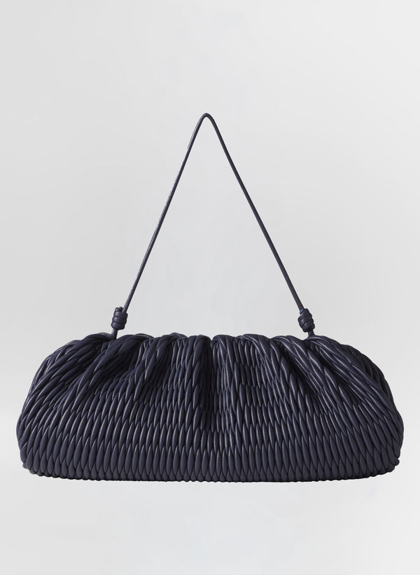 Navy blue quilted handbag with a strap on a light gray background