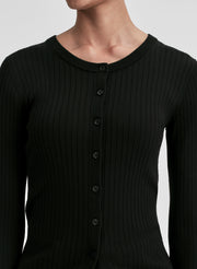 Person wearing a black ribbed long-sleeve cardigan and pants on a light gray background