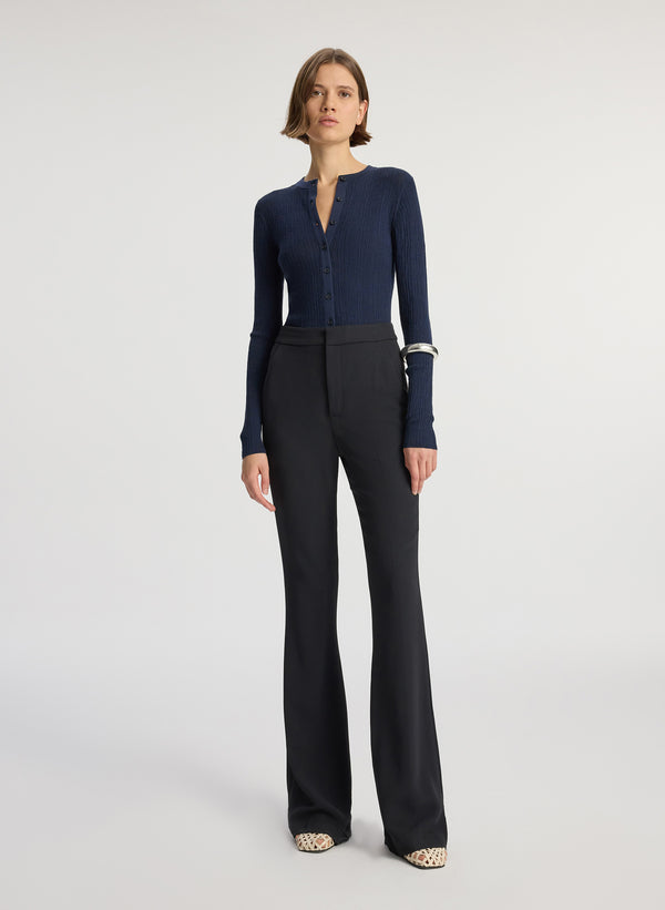 front view of woman wearing navy cardigan and black flared pants