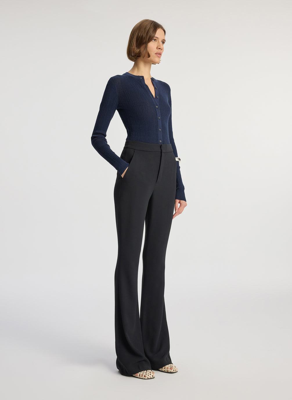 side view of woman wearing navy cardigan and black flared pants