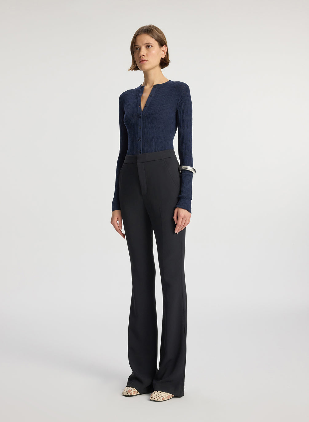 side view of woman wearing navy cardigan and black flared pants
