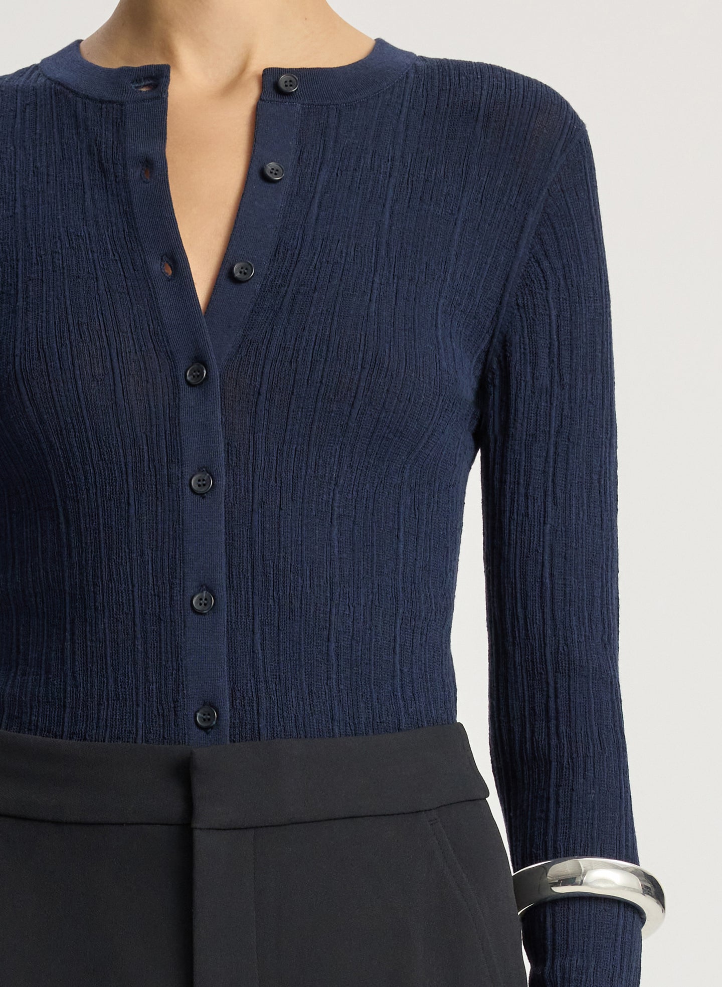 detail view of woman wearing navy cardigan and black flared pants