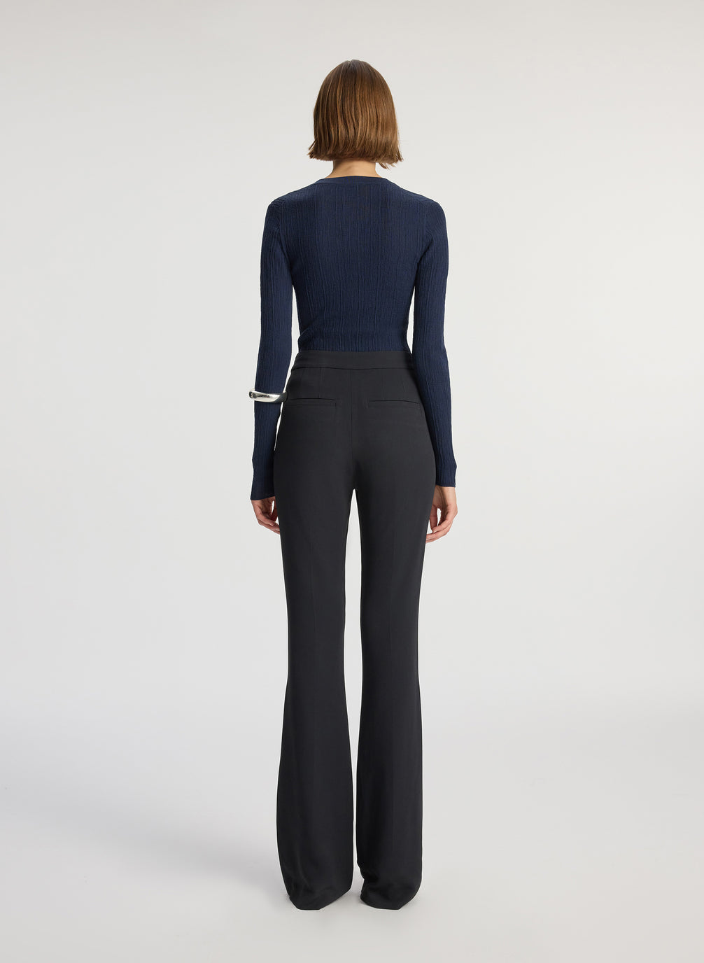 back view of woman wearing navy cardigan and black flared pants