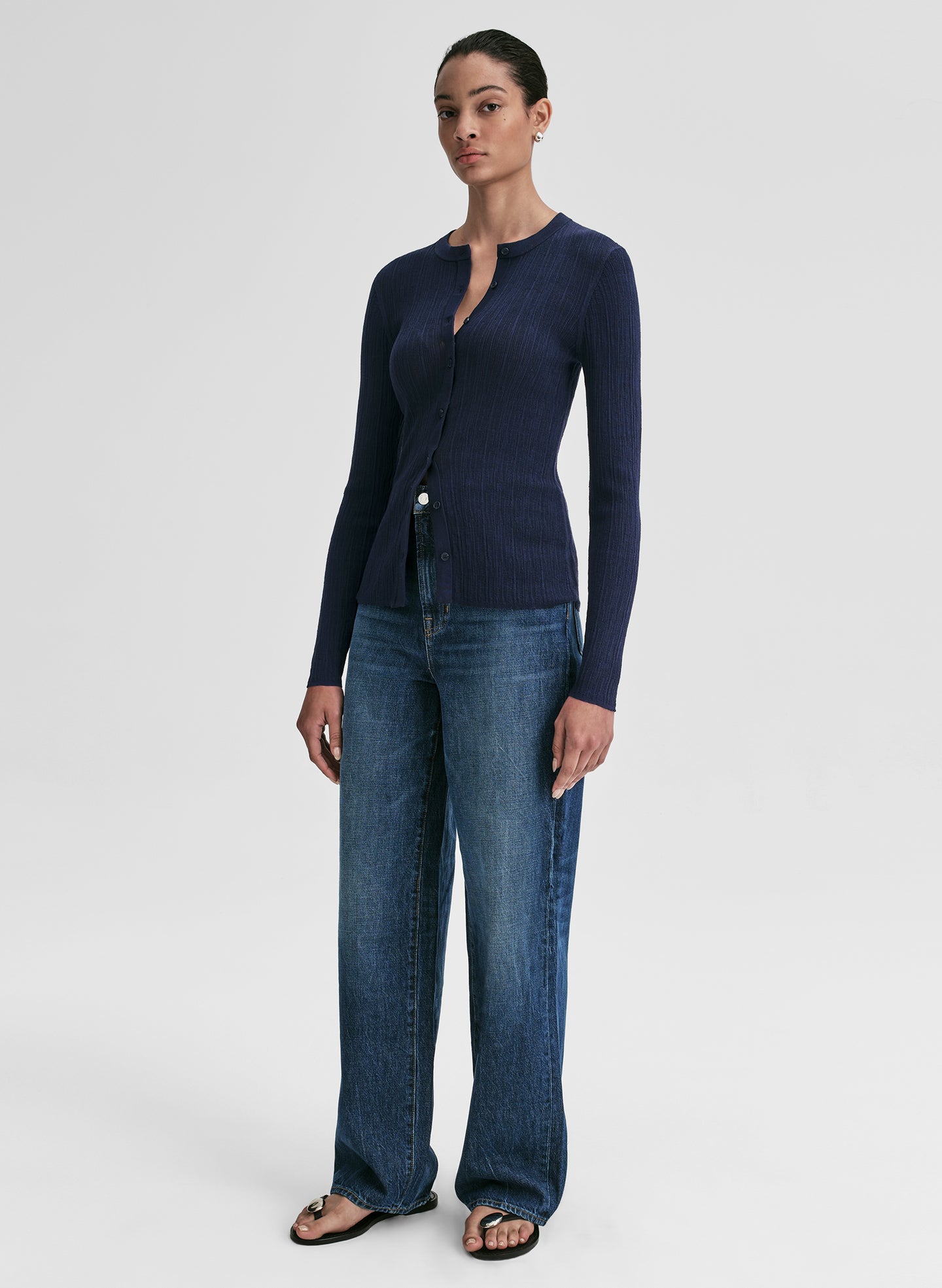 Woman wearing a navy cardigan and blue jeans on a white background