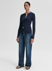 Woman wearing a navy cardigan and blue jeans on a white background