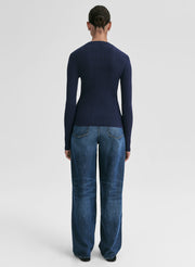 Person wearing a navy sweater and blue jeans on a white background