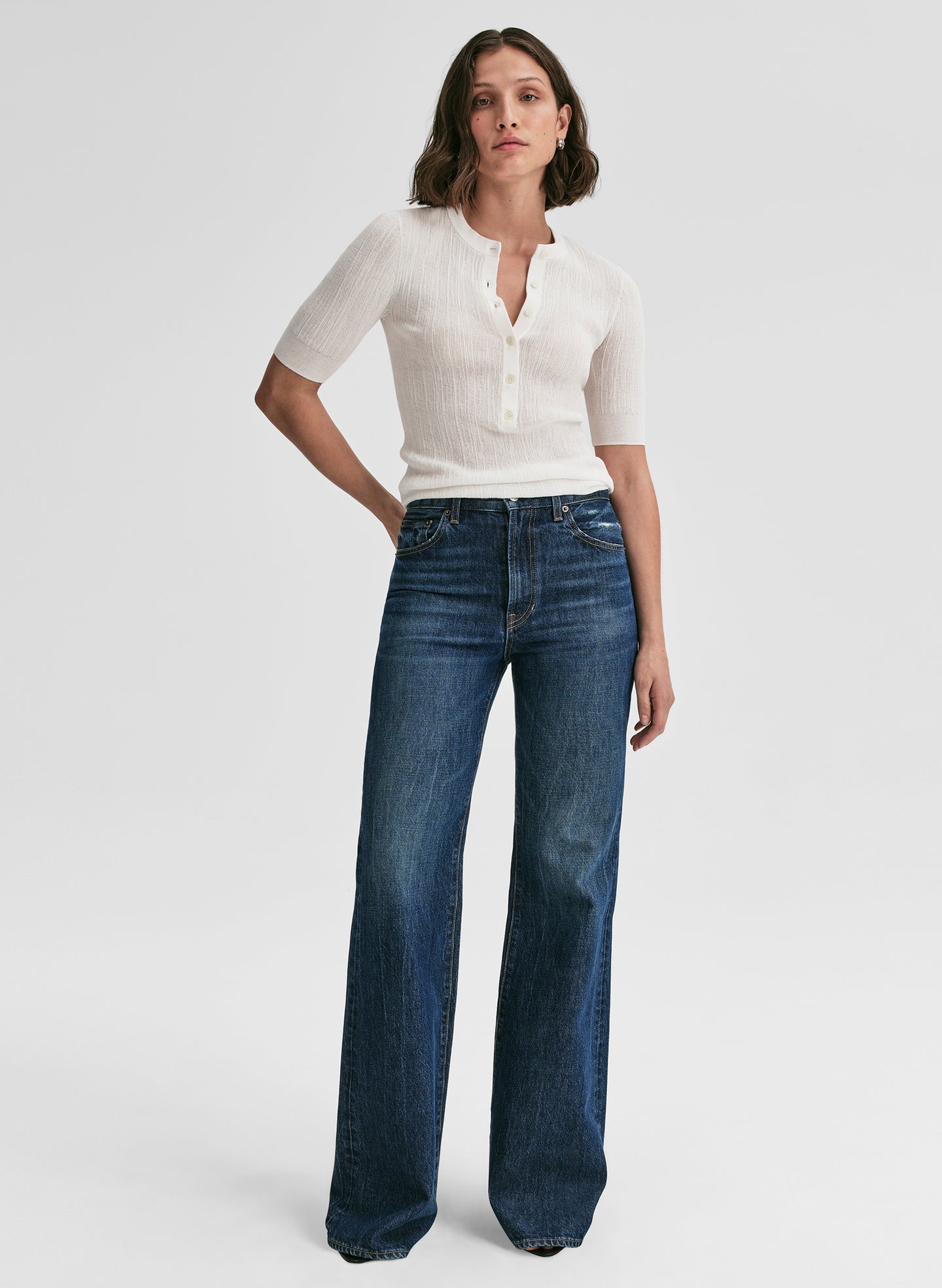 Woman wearing a white top and blue jeans on a white background