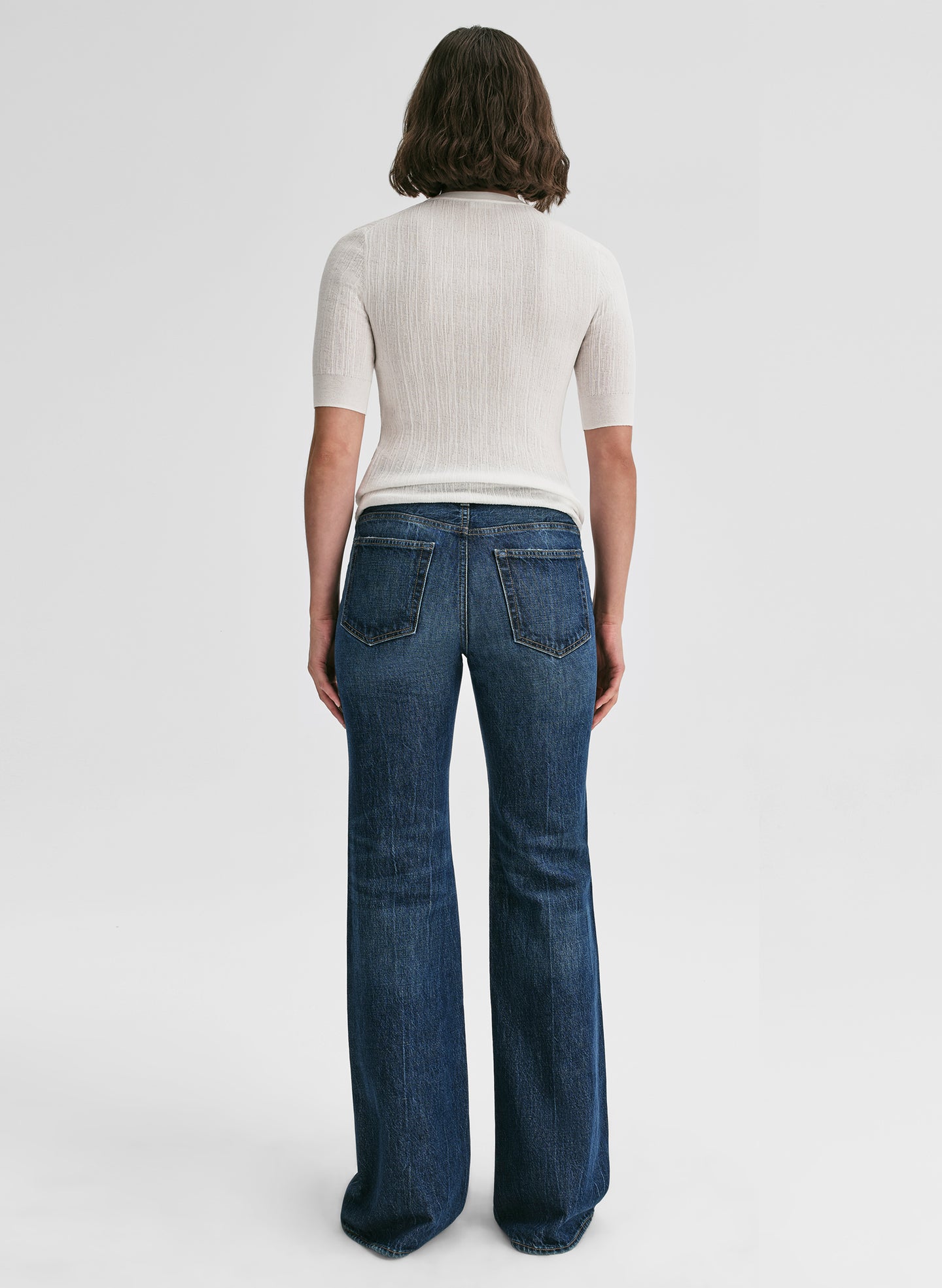 Person wearing blue jeans and a white top on a white background