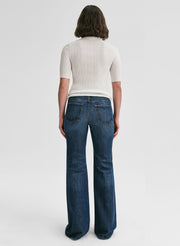 Person wearing blue jeans and a white top on a white background