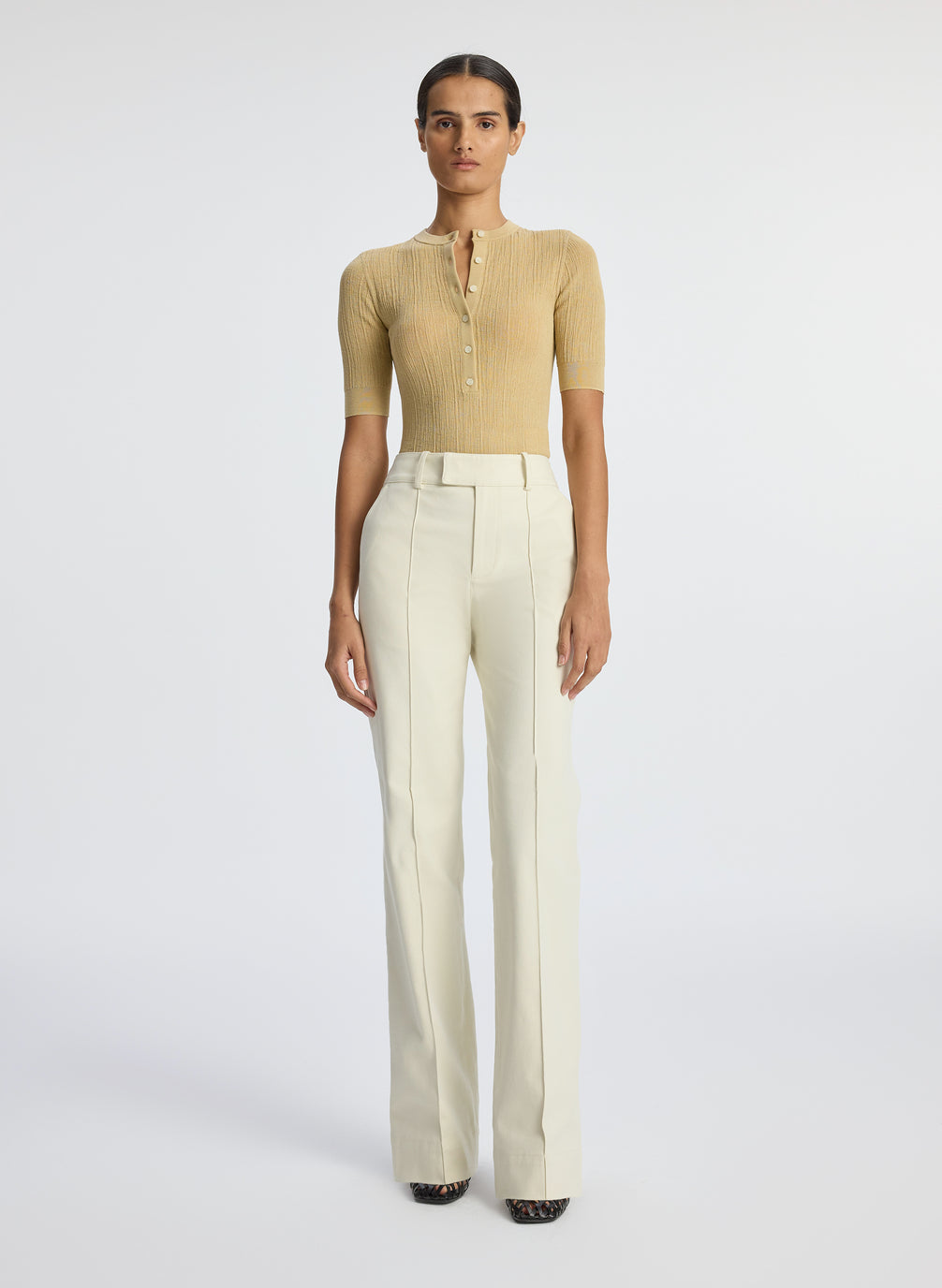 front  view of woman wearing beige half sleeve button placket shirt and cream pants
