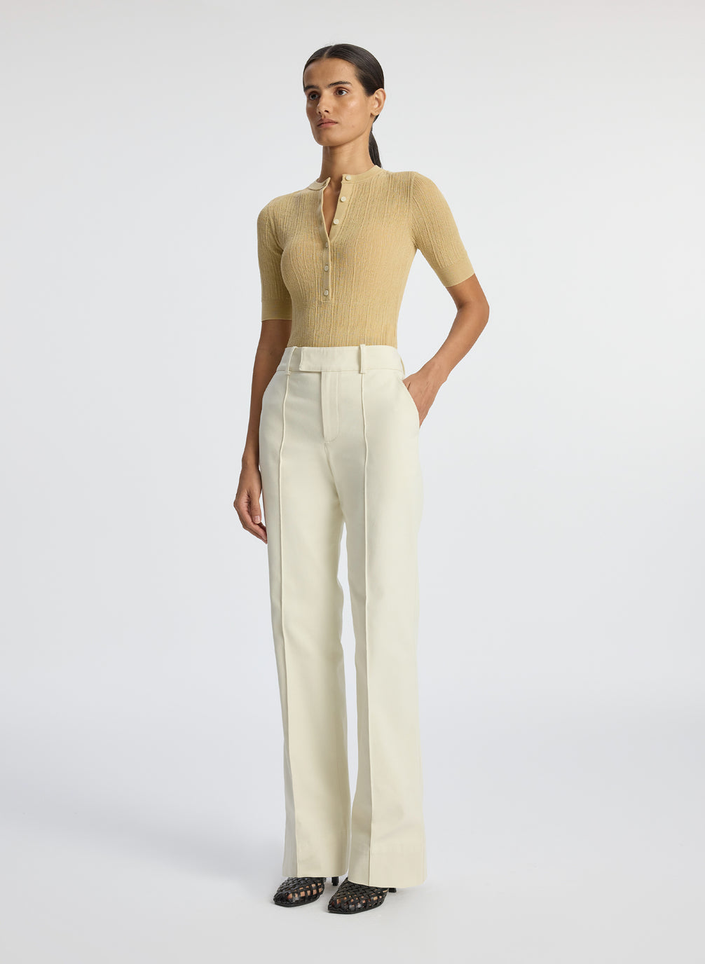 side  view of woman wearing beige half sleeve button placket shirt and cream pants