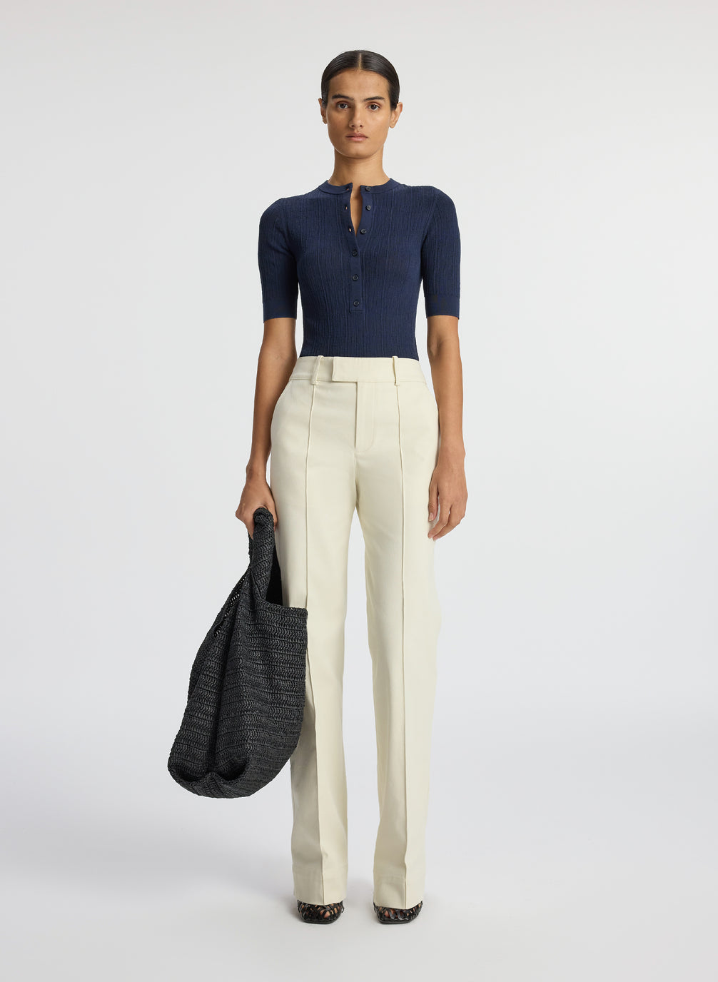 front view of woman wearing navy blue half sleeve button placket shirt and cream pants