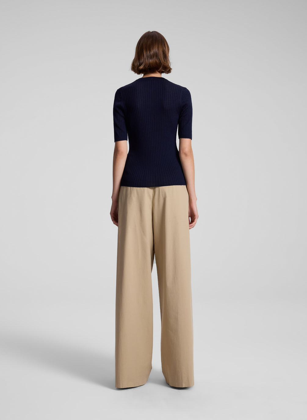 woman wearing navy blue top and tan wide leg pants