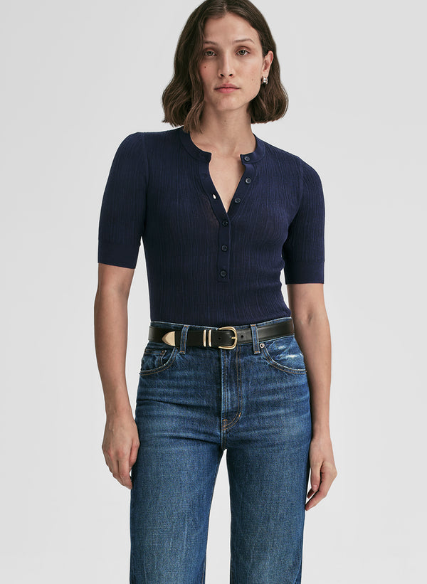 Woman wearing a navy blue top and blue jeans on a white background