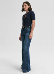 Woman wearing a navy top and blue jeans on a white background