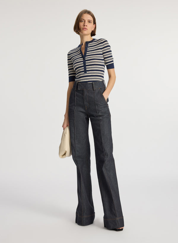 front view of woman wearing navy blue striped half sleeve button placket shirt and dark wash raw denim jean