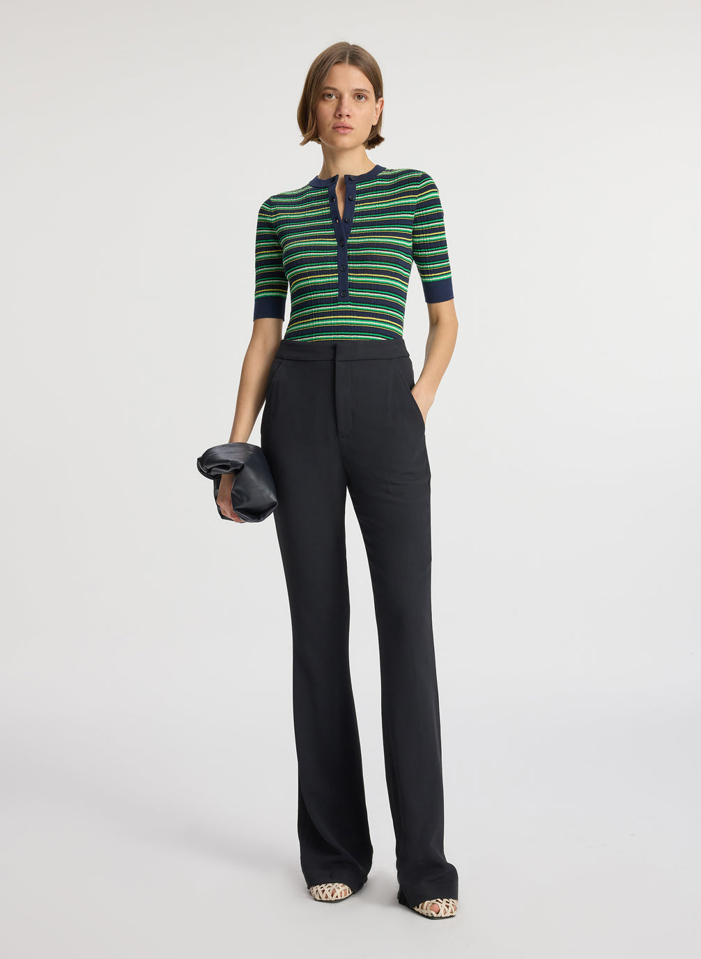 front view of woman wearing navy blue and green striped half sleeve button placket shirt and black pant