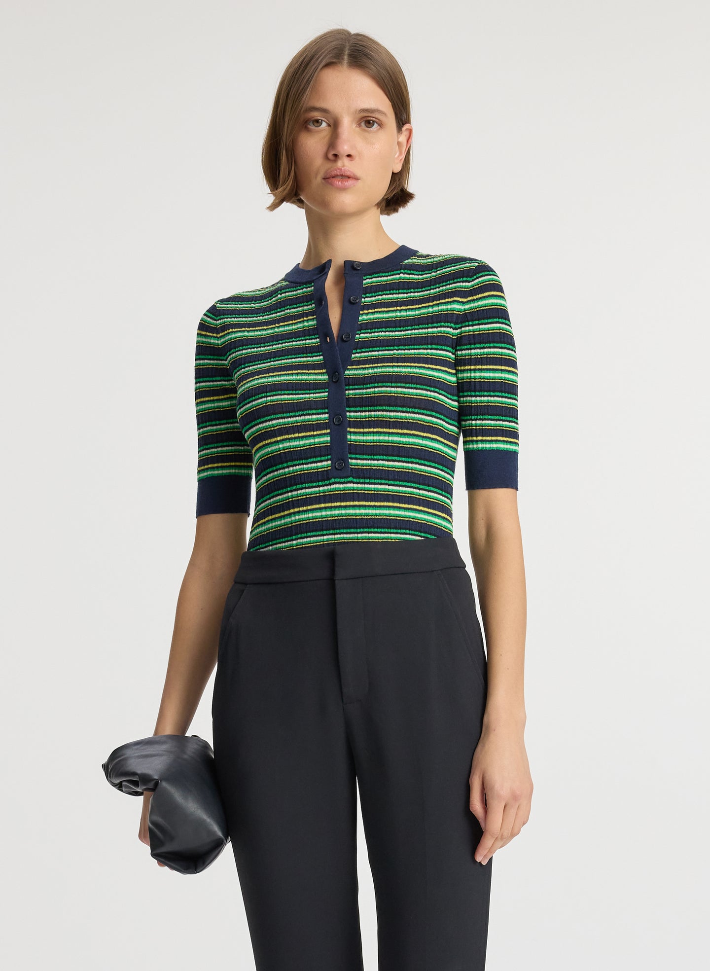 detail  view of woman wearing navy blue and green striped half sleeve button placket shirt and black pant