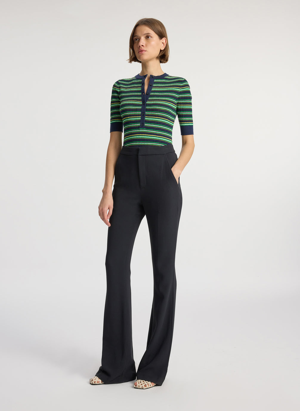 front view of woman wearing navy blue and green striped half sleeve button placket shirt and black pant
