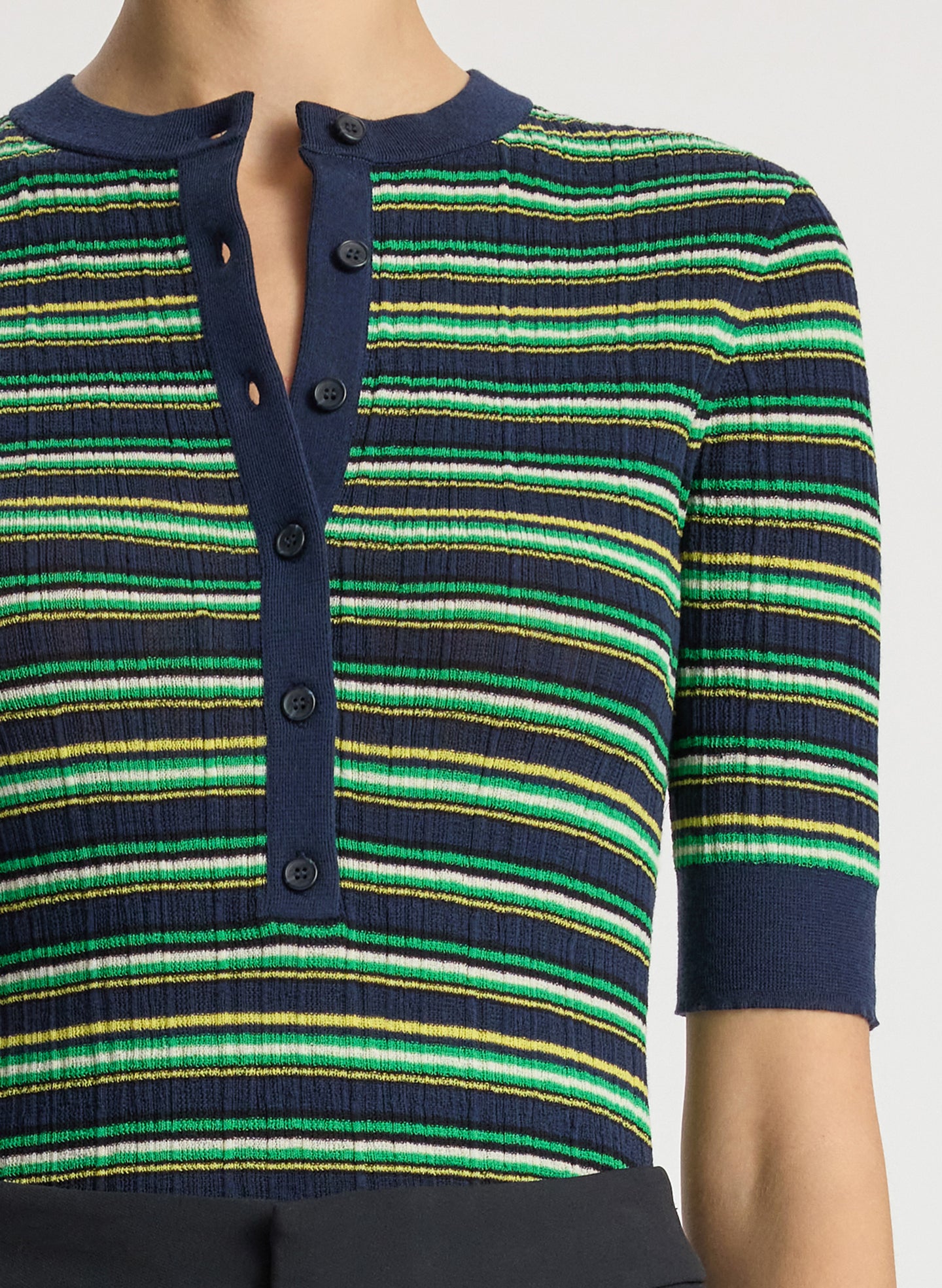 detail  view of woman wearing navy blue and green striped half sleeve button placket shirt and black pant