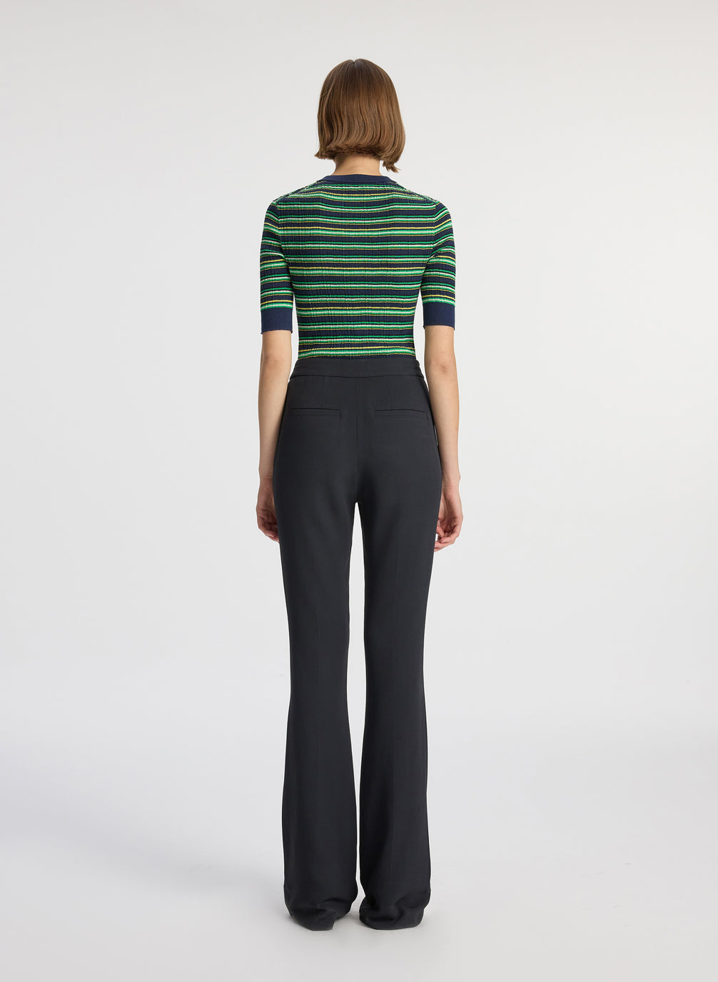 back  view of woman wearing navy blue and green striped half sleeve button placket shirt and black pant