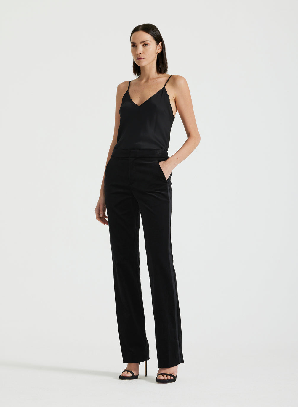 side view of woman wearing black satin camisole and black velvet pants