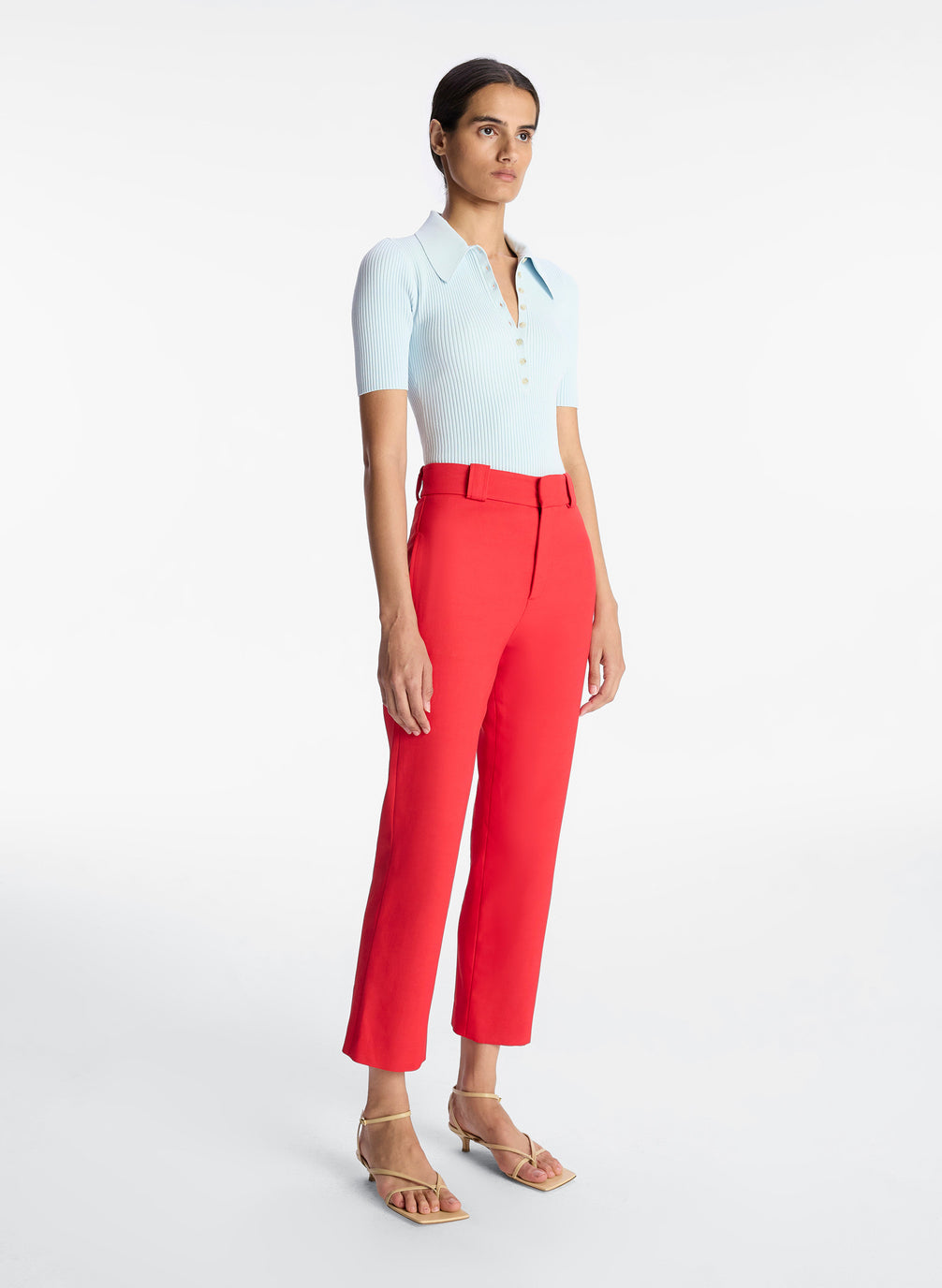 side view of woman wearing light blue collared shirt and red ankle pant