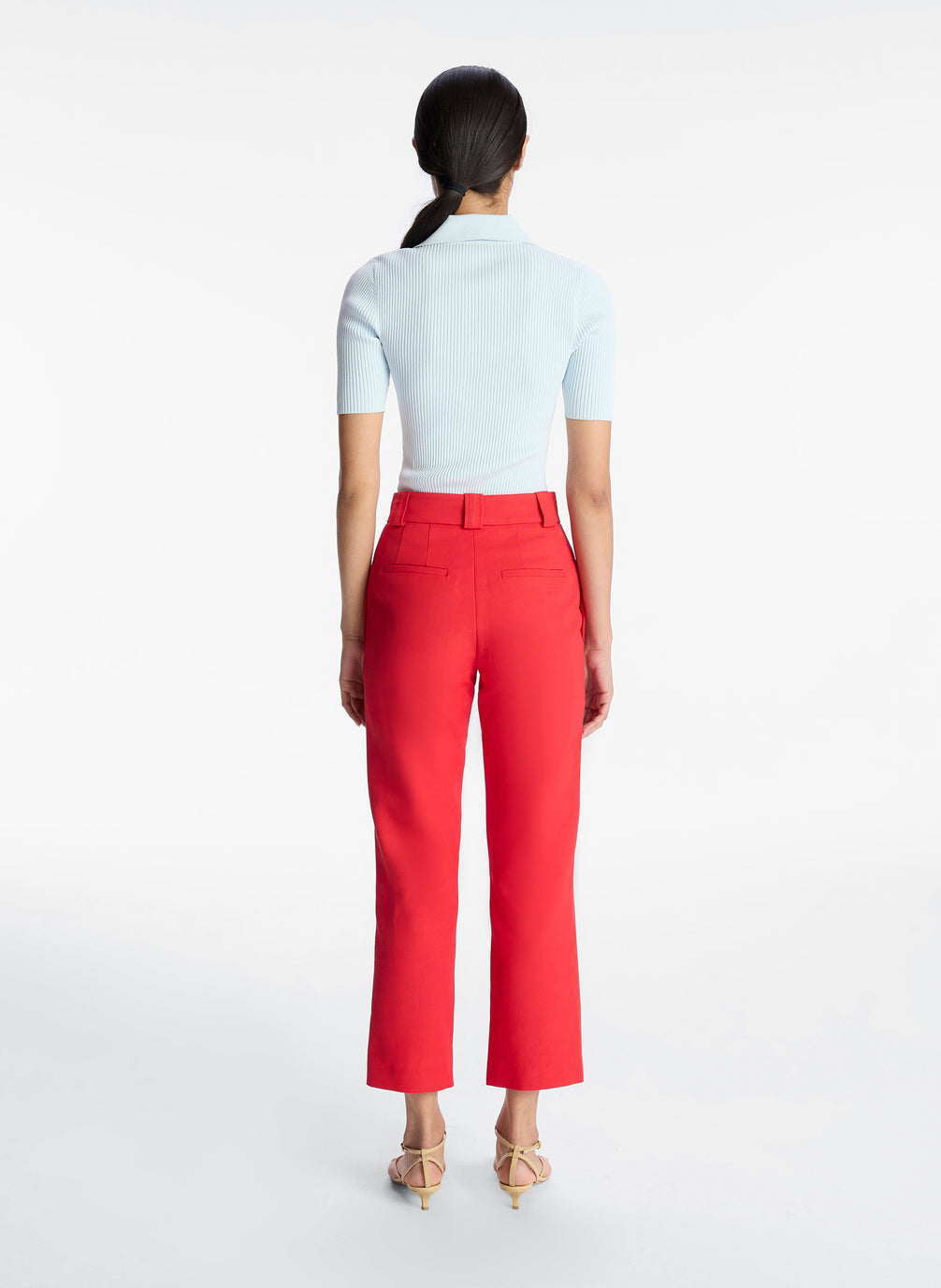 back view of woman wearing light blue collared shirt and red ankle pant