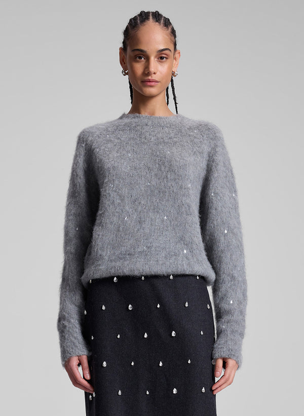 woman wearing grey embellished sweater and black embellished skirt