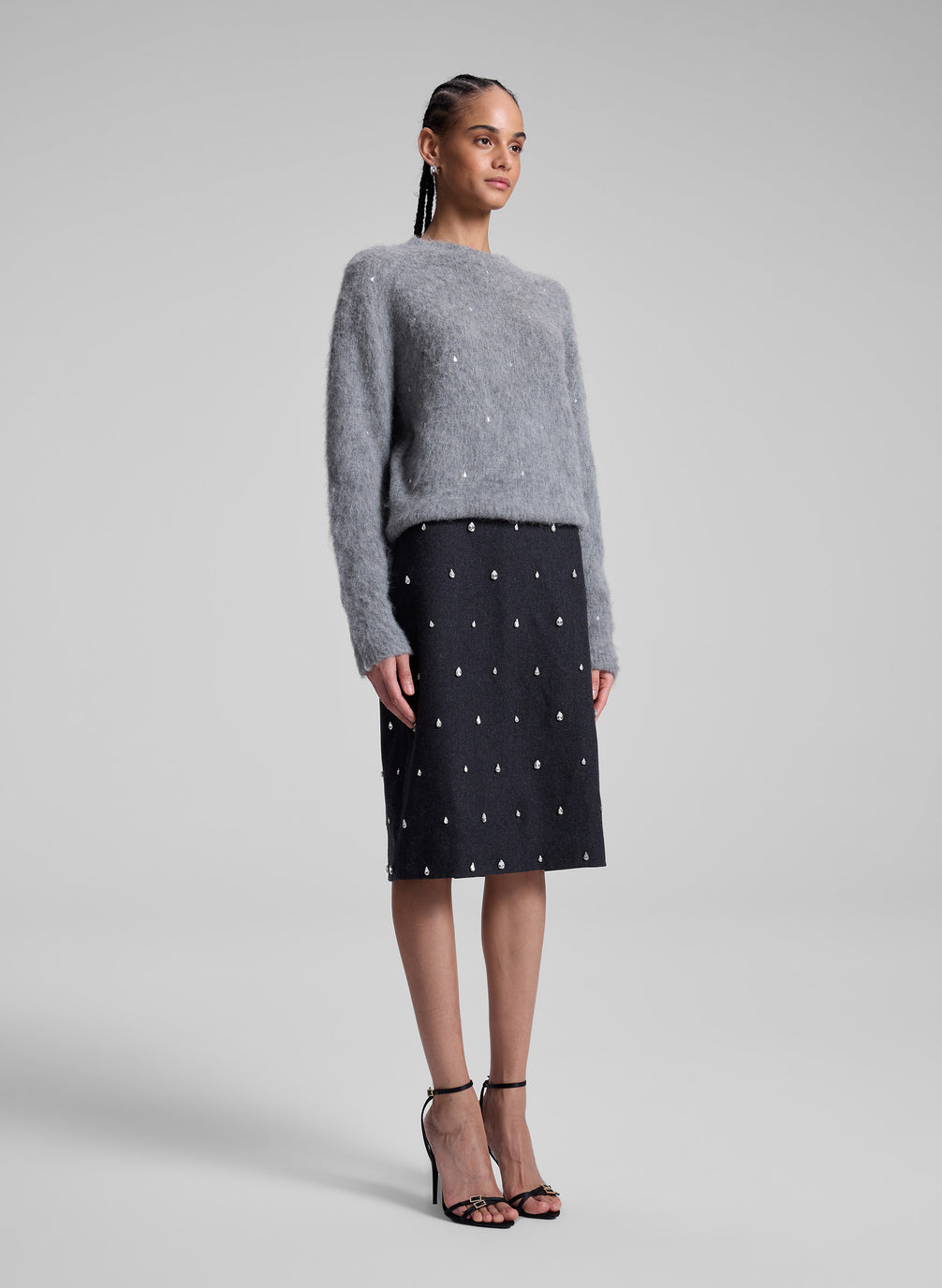 woman wearing grey embellished sweater and black embellished skirt