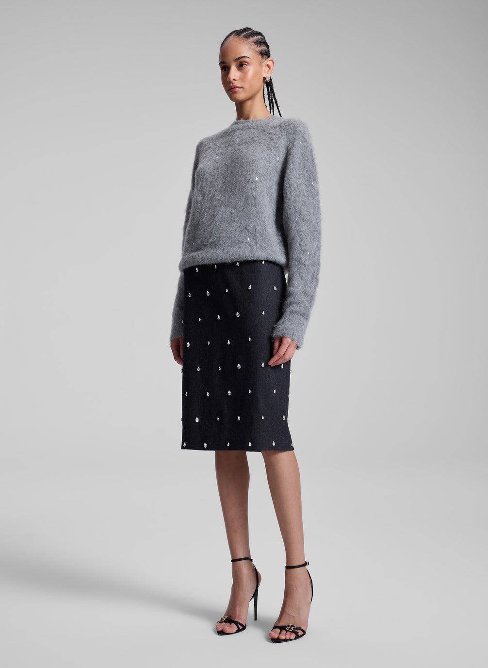 woman wearing grey embellished sweater and black embellished skirt