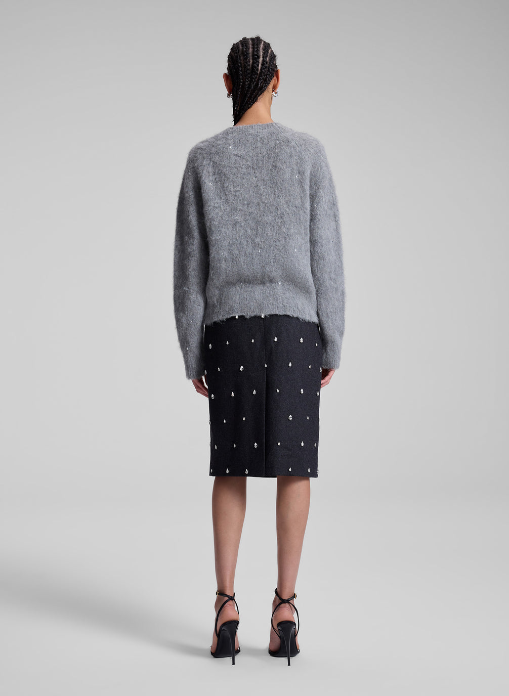 woman wearing grey embellished sweater and black embellished skirt