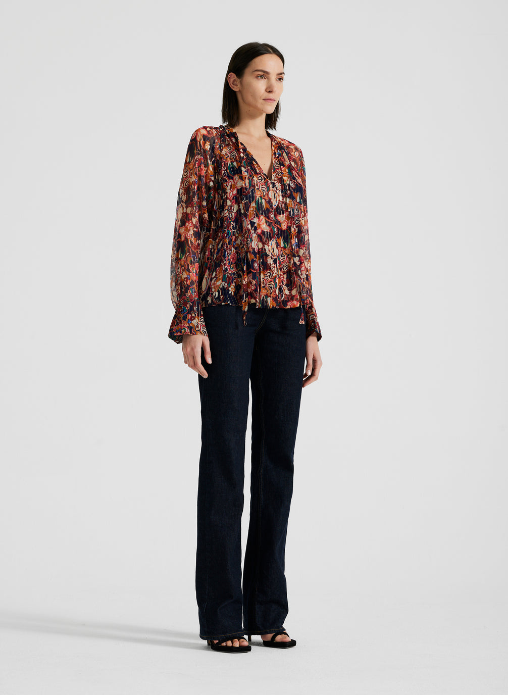 side view of woman wearing silk long sleeve printed blouse and black pants