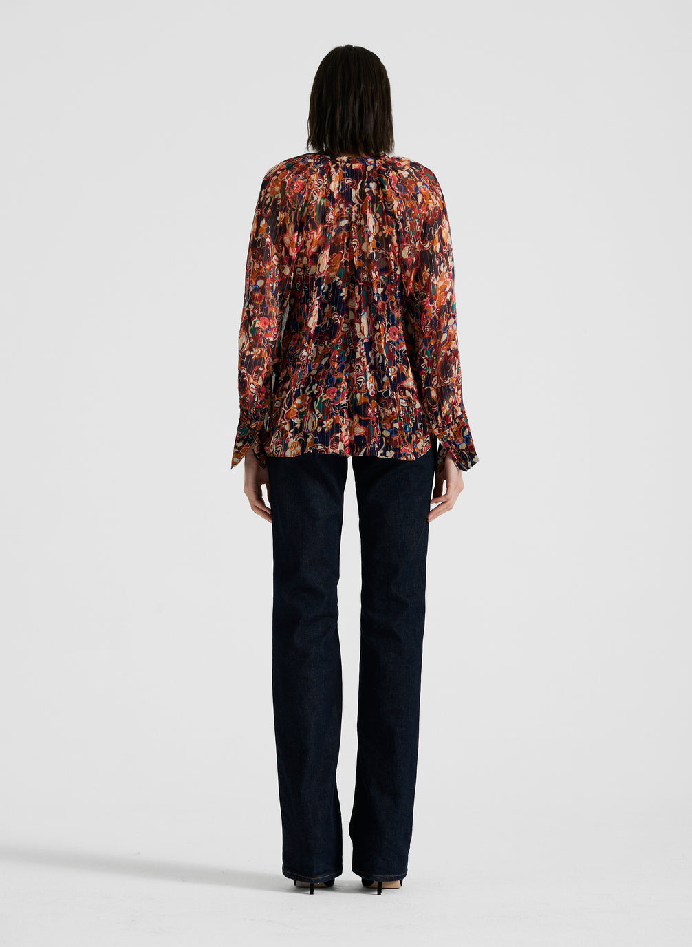 back view of woman wearing silk long sleeve printed blouse and black pants