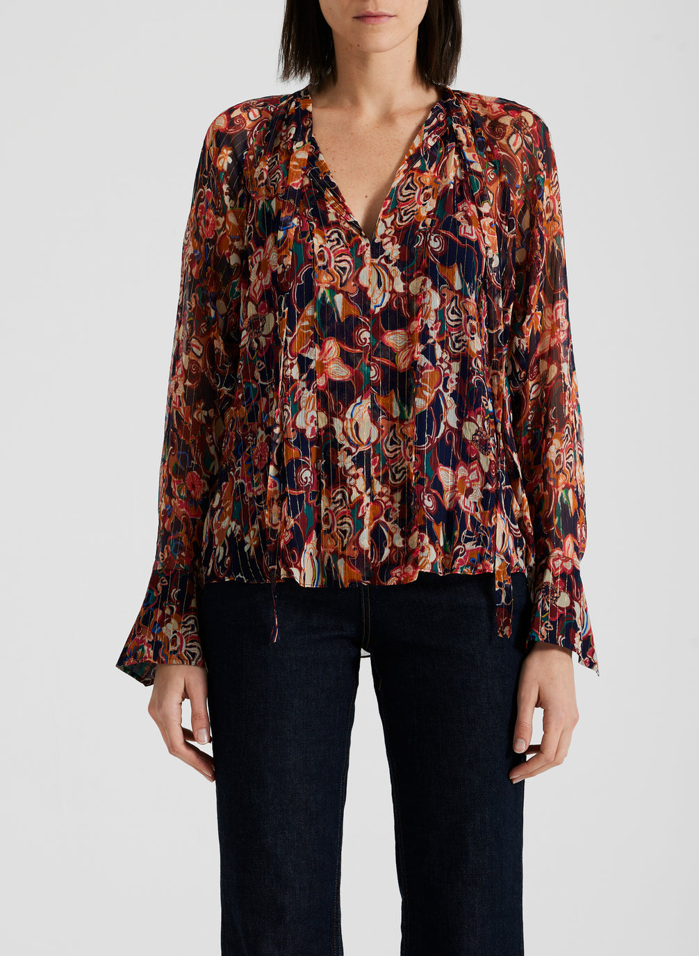 detail view of woman wearing silk long sleeve printed blouse and black pants