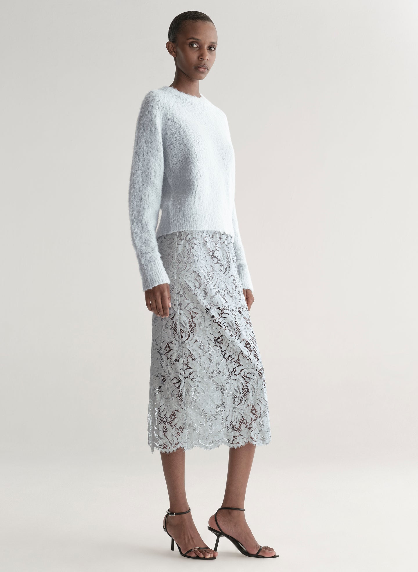 woman wearing light blue sweater with light blue lace skirt