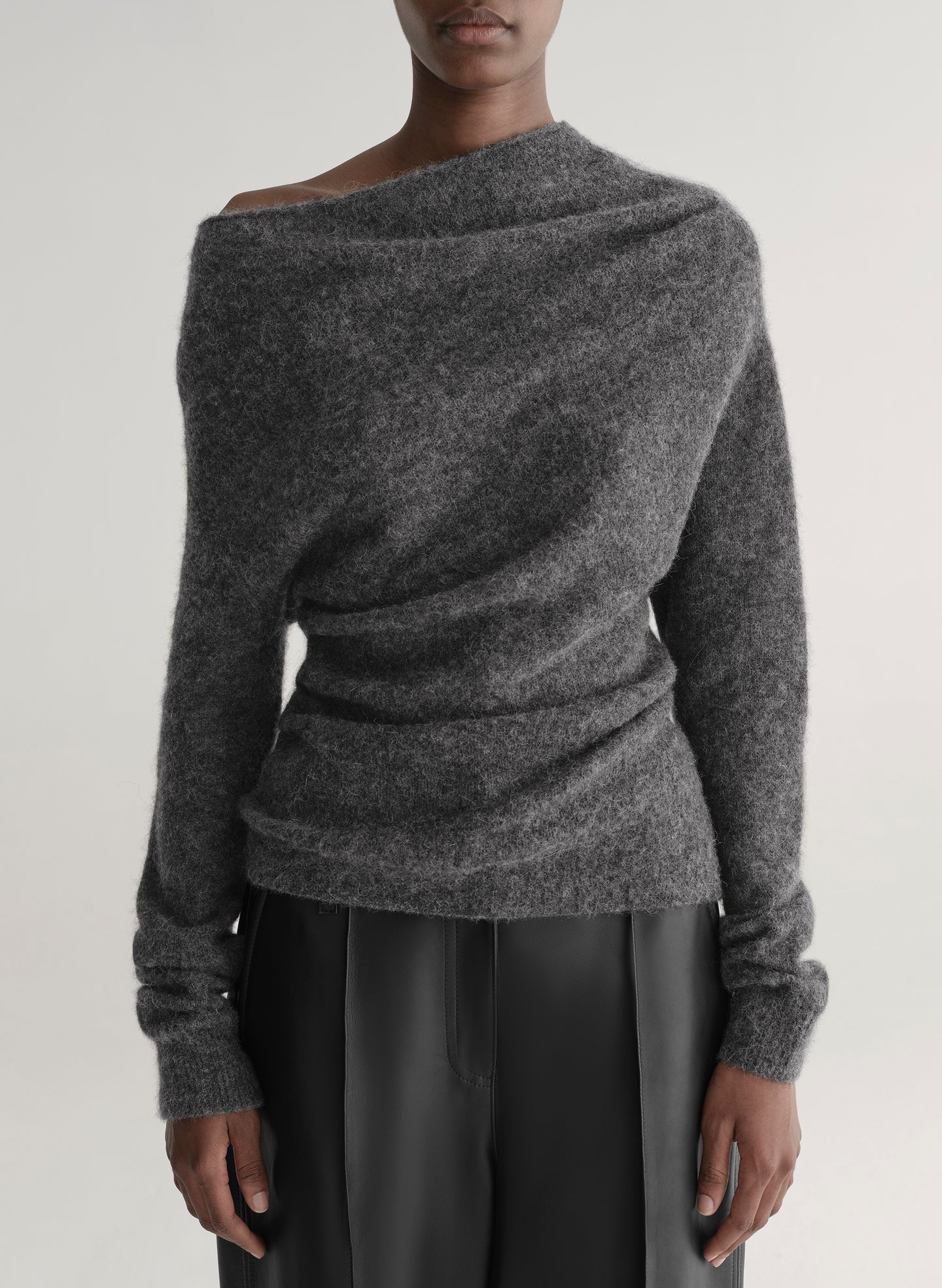 Person wearing a gray off-shoulder sweater against a plain background