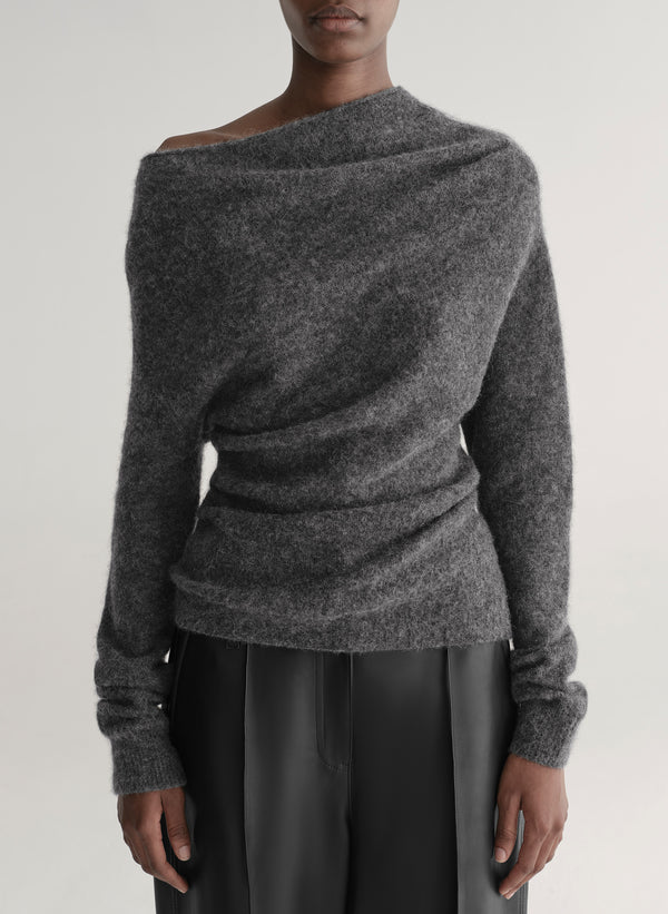 Person wearing a gray off-shoulder sweater against a plain background