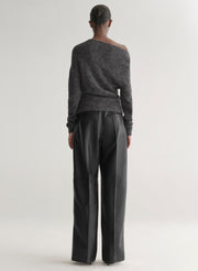 Person wearing a gray off-shoulder sweater and black pants on a white background