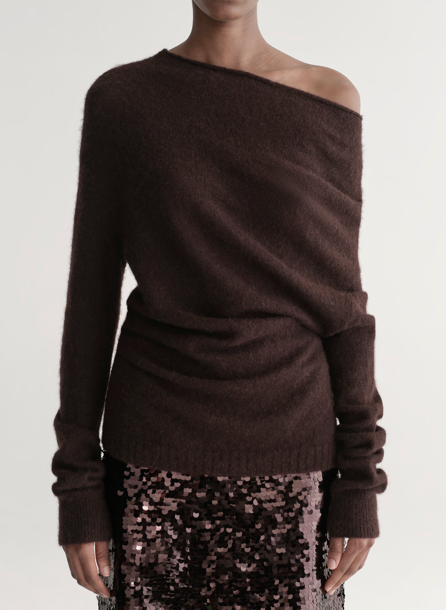 Woman wearing a brown off-shoulder sweater with a sequined midi skirt