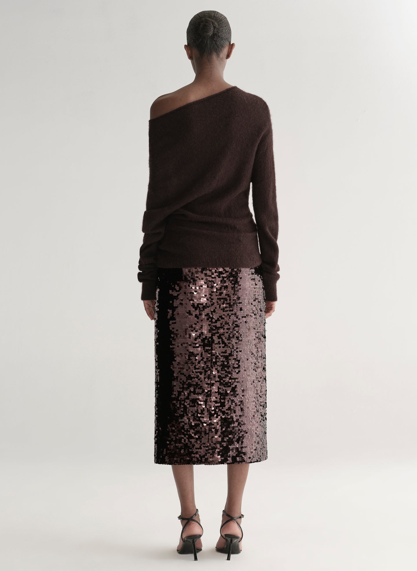 Woman wearing a brown off-shoulder sweater with a sequined midi skirt