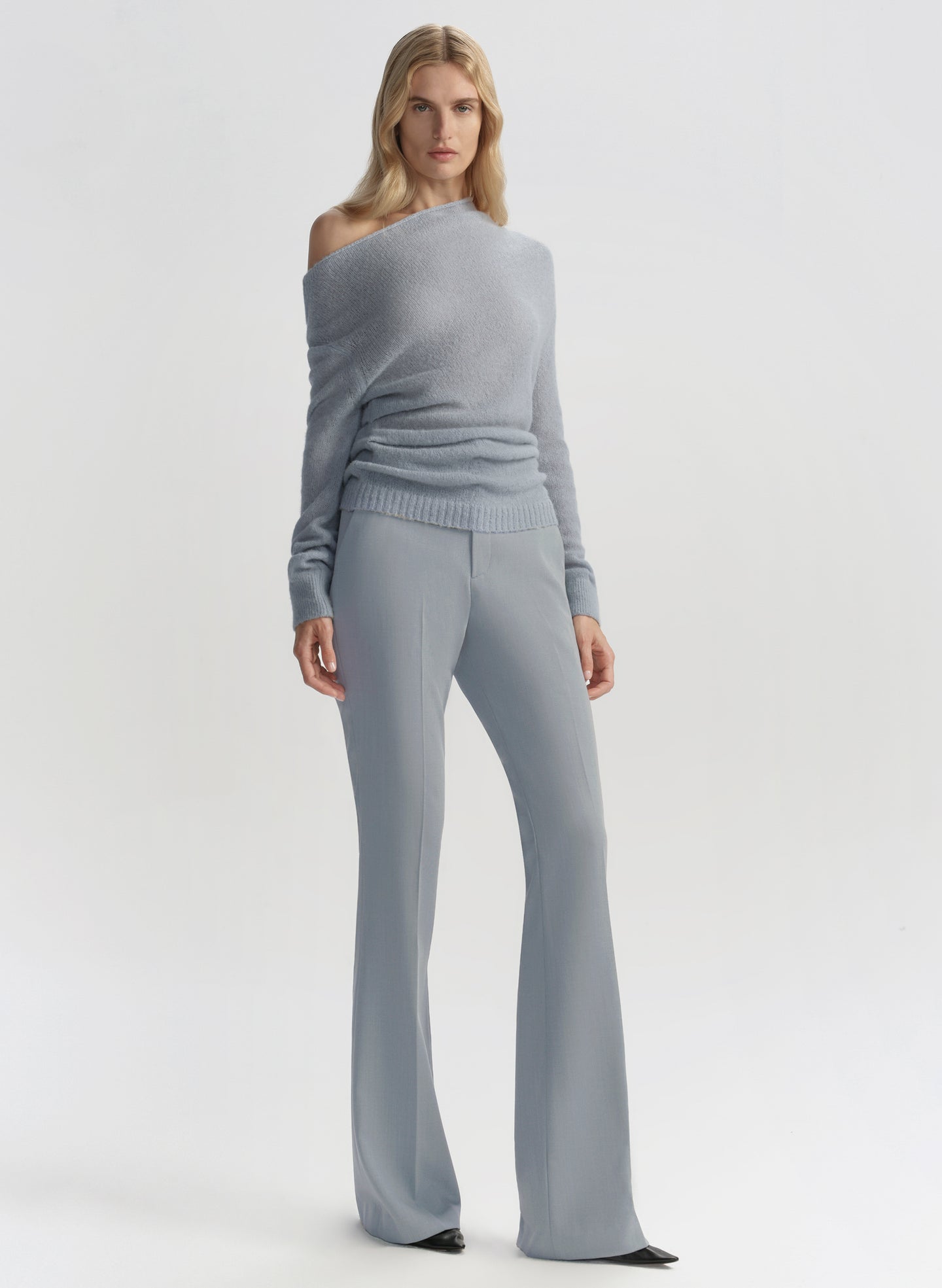 Woman wearing a gray off-shoulder top and wide-leg pants on a white background