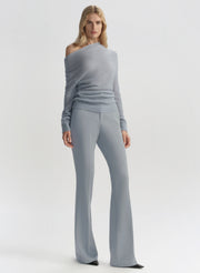 Woman wearing a gray off-shoulder top and wide-leg pants on a white background