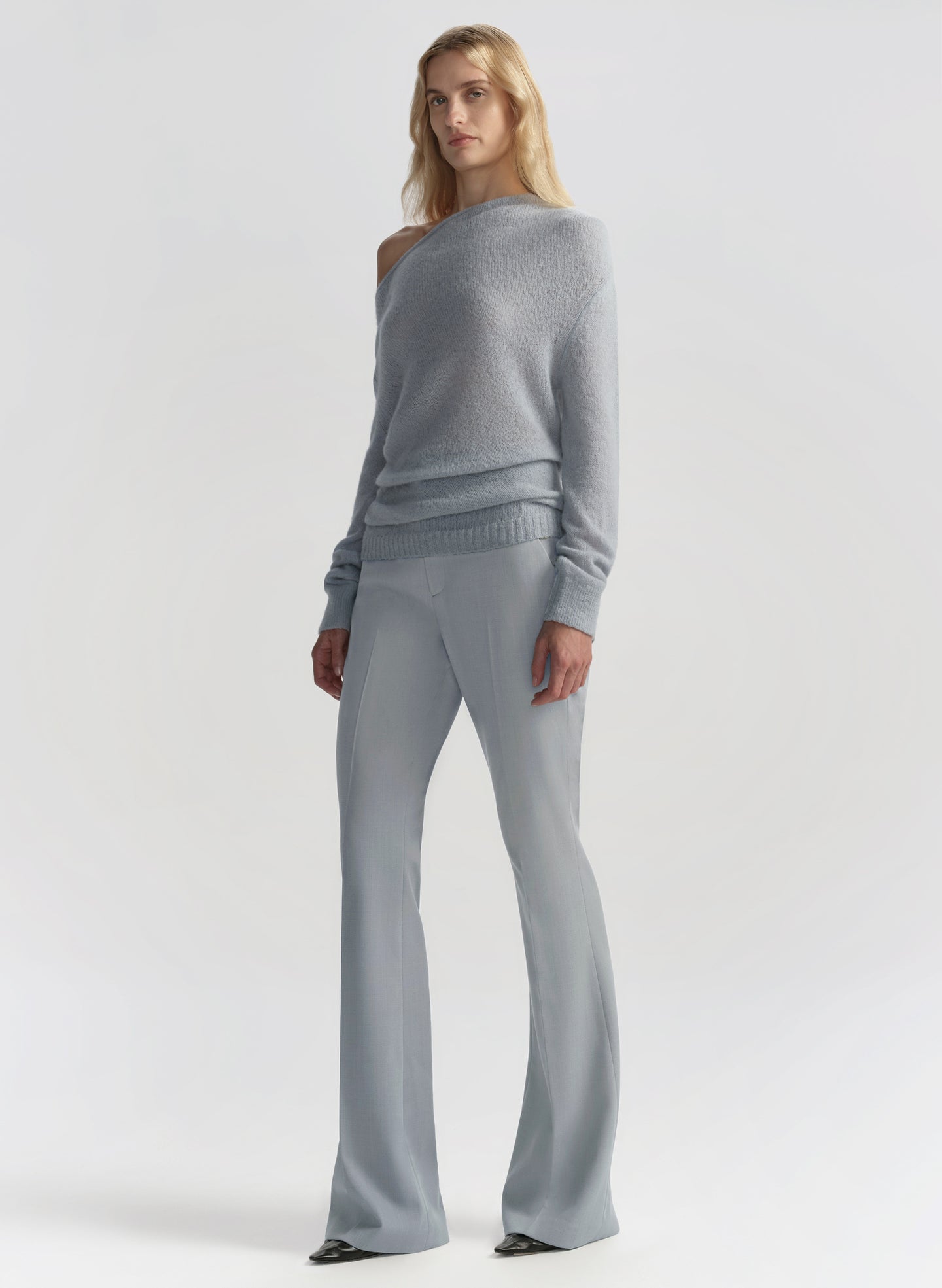 Woman wearing a gray sweater and pants on a white background