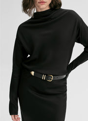 Person wearing a black long-sleeve top with a belt on a white background