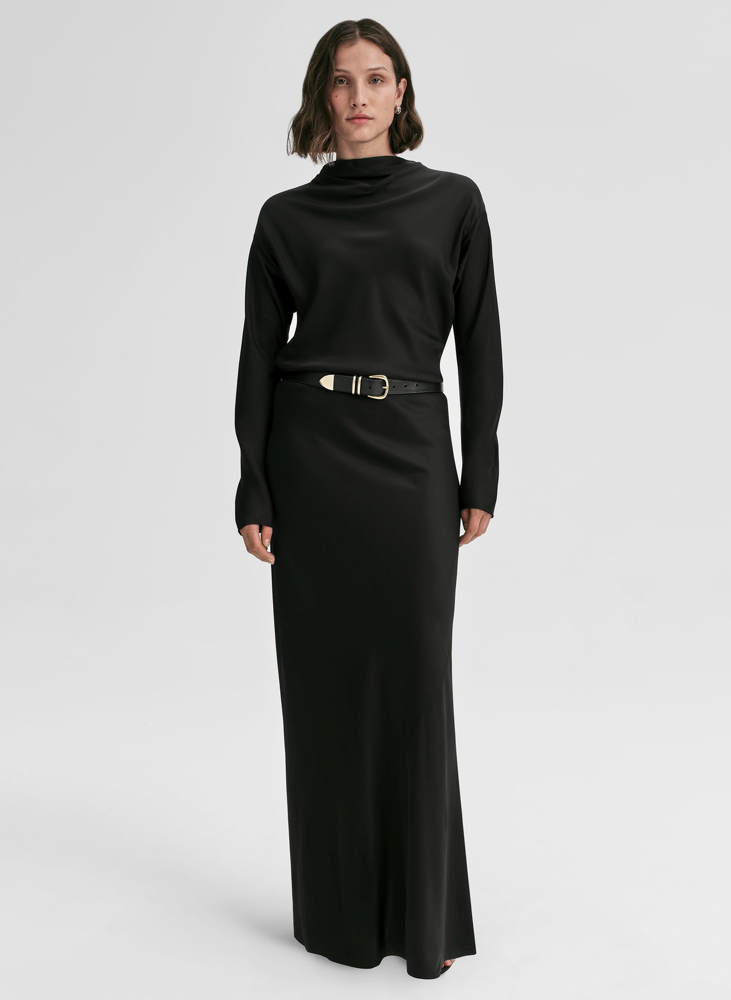 Woman wearing a black long-sleeve dress with a belt on a white background