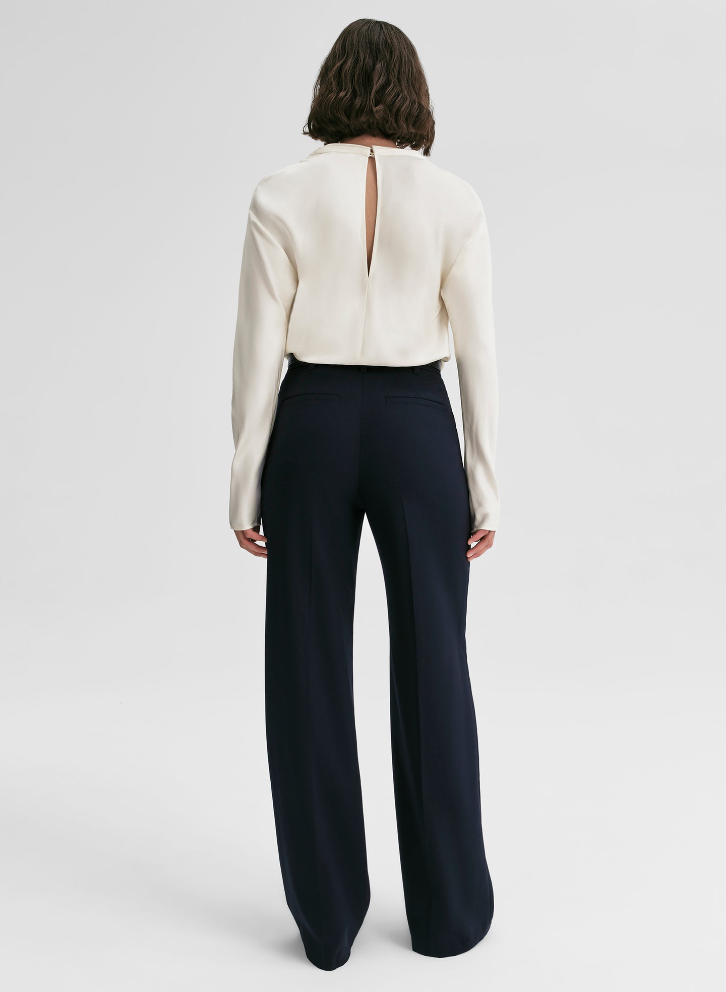 woman wearing white satin top and navy blue pants