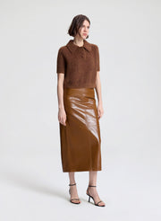 Woman wearing a brown top and leather skirt on a white background